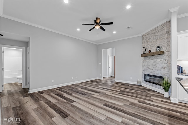 unfurnished living room featuring a stone fireplace, crown molding, ceiling fan, and hardwood / wood-style flooring