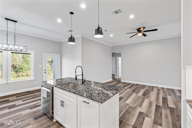 kitchen with dark stone countertops, white cabinetry, sink, and hanging light fixtures