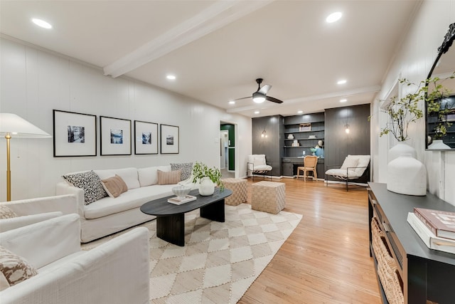 living room with beam ceiling, light hardwood / wood-style flooring, ceiling fan, and crown molding