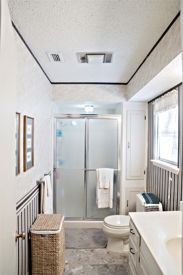 bathroom featuring vanity, toilet, an enclosed shower, and a textured ceiling