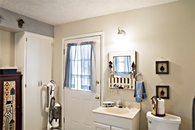 bathroom featuring vanity, a textured ceiling, and toilet