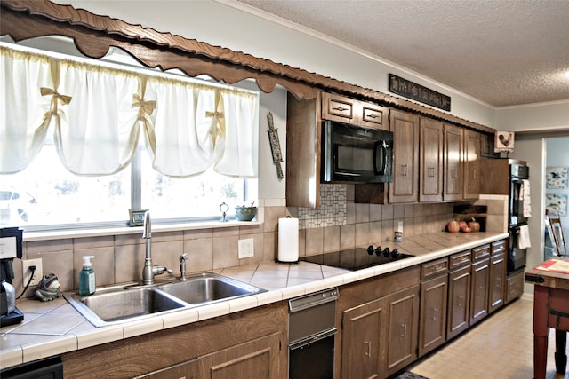 kitchen with black appliances, tile counters, decorative backsplash, and sink