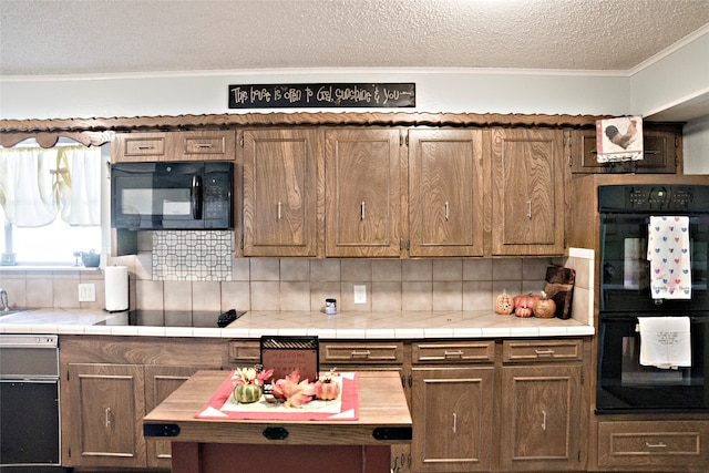 kitchen featuring tile countertops, tasteful backsplash, ornamental molding, and black appliances