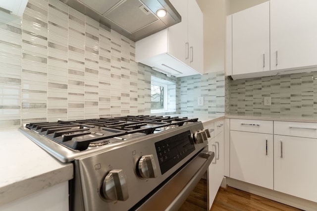 kitchen with backsplash, white cabinetry, hardwood / wood-style flooring, and stainless steel gas range