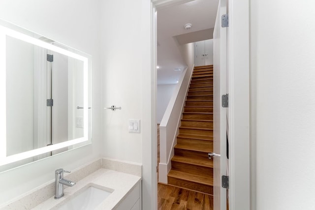 stairs featuring wood-type flooring and sink