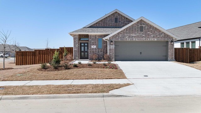 view of front facade with brick siding, concrete driveway, fence, and an attached garage