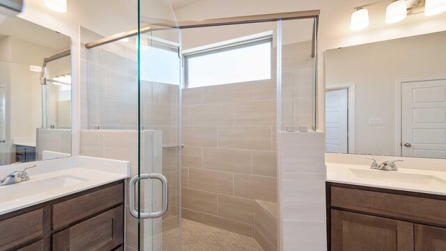 full bath featuring a shower stall, a sink, and two vanities