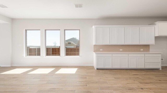 interior space featuring visible vents, light countertops, light wood-style flooring, and white cabinetry