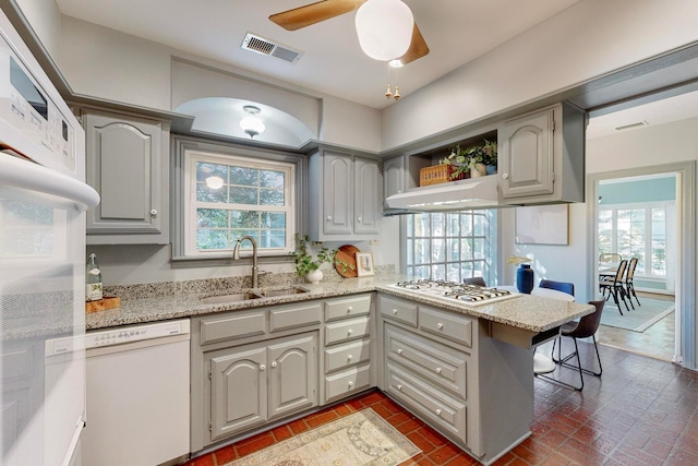 kitchen with gray cabinetry, ceiling fan, sink, kitchen peninsula, and white appliances