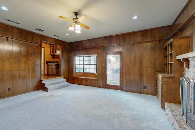 unfurnished living room with ceiling fan, light carpet, and wooden walls