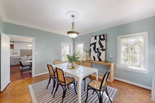 dining room featuring plenty of natural light, ornamental molding, and light parquet flooring