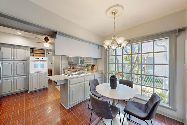 kitchen featuring gray cabinetry, kitchen peninsula, stainless steel appliances, and hanging light fixtures