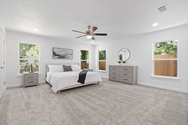 bedroom featuring light carpet, multiple windows, and ceiling fan