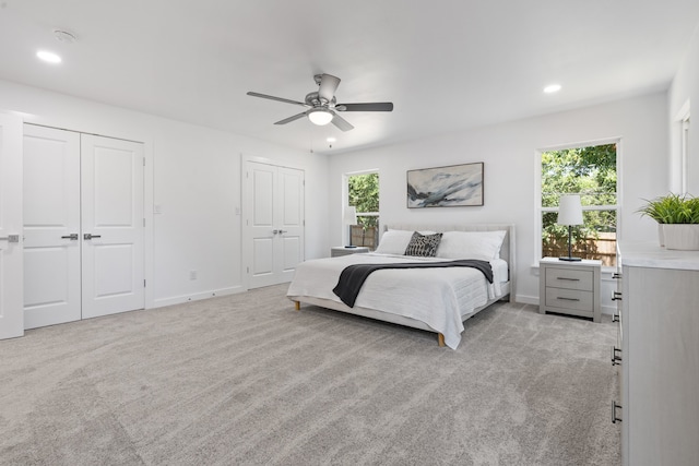 carpeted bedroom featuring ceiling fan and multiple closets