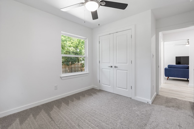 unfurnished bedroom featuring ceiling fan, light colored carpet, and a closet