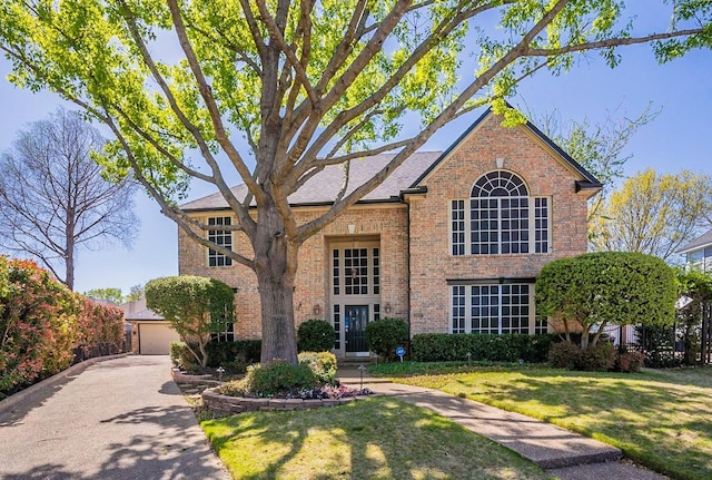 tudor-style house featuring a garage and a front yard