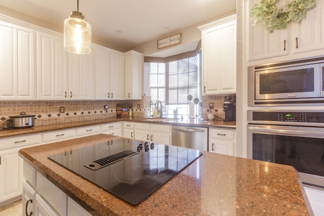 kitchen with white cabinets, stainless steel appliances, dark stone counters, and sink