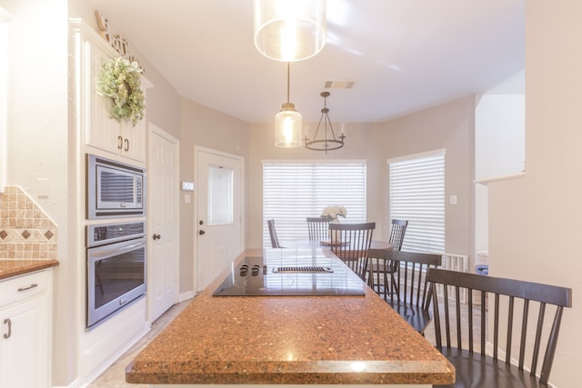 kitchen featuring a notable chandelier, white cabinets, hanging light fixtures, stone countertops, and stainless steel appliances