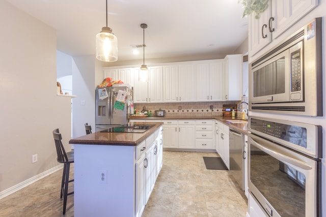 kitchen featuring white cabinetry, a center island, sink, stainless steel appliances, and backsplash