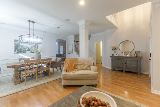 living room featuring light wood-type flooring, ornamental molding, and a chandelier