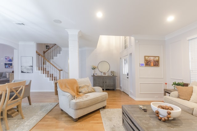 living room with decorative columns, light hardwood / wood-style floors, and ornamental molding