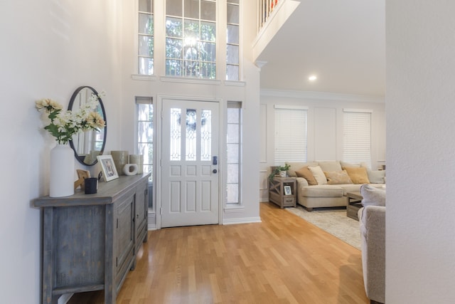 entryway with ornamental molding, a high ceiling, and hardwood / wood-style flooring