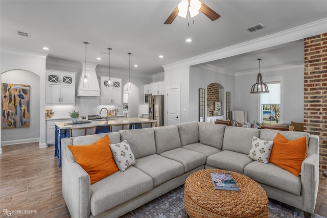 living room with crown molding, sink, ceiling fan, and dark wood-type flooring