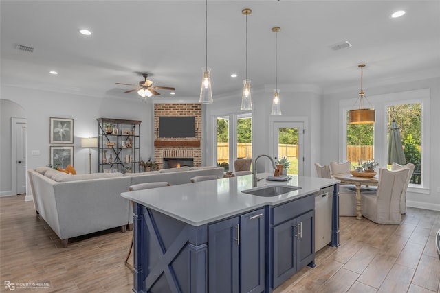 kitchen with a kitchen island with sink, a healthy amount of sunlight, sink, pendant lighting, and a fireplace