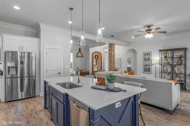 kitchen with appliances with stainless steel finishes, hardwood / wood-style flooring, white cabinetry, and pendant lighting