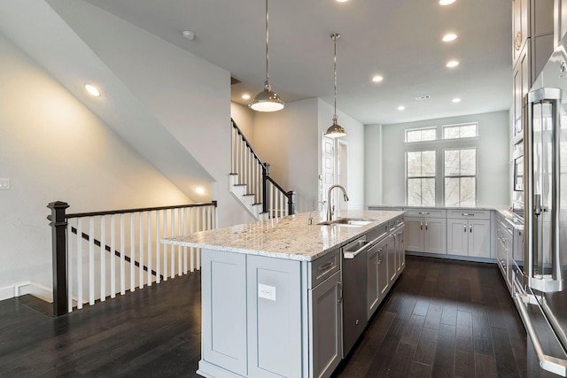 kitchen with sink, stainless steel appliances, dark hardwood / wood-style flooring, decorative light fixtures, and a kitchen island with sink