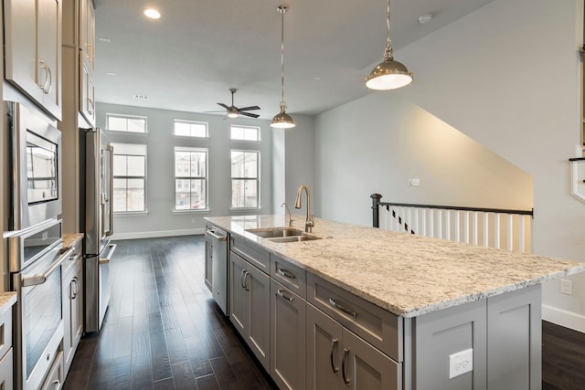 kitchen featuring gray cabinets, sink, a center island with sink, and appliances with stainless steel finishes