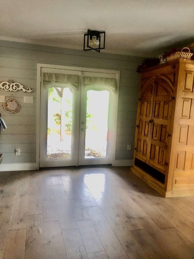 doorway to outside featuring wood walls, light hardwood / wood-style flooring, and french doors