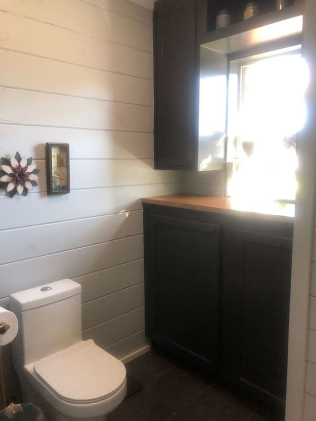 bathroom with vanity, toilet, and wooden walls