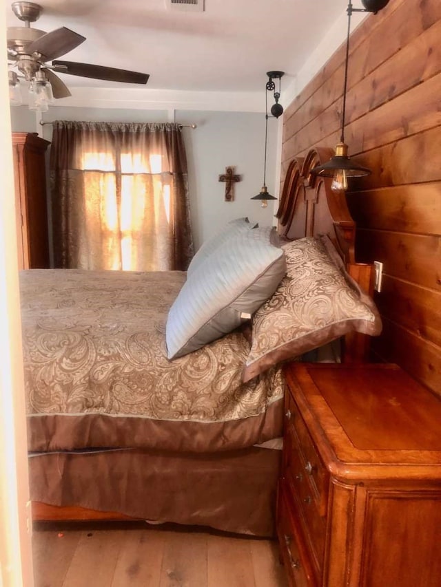 bedroom with wood walls, ceiling fan, and hardwood / wood-style flooring