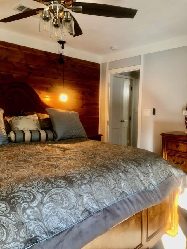 bedroom featuring ceiling fan and wooden walls