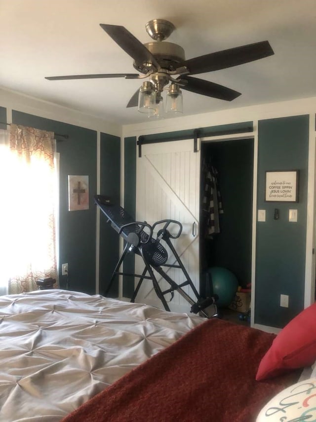 bedroom with a barn door, a closet, ceiling fan, and crown molding