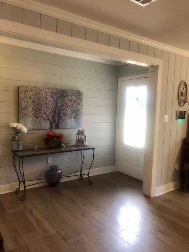 foyer with wood walls, dark hardwood / wood-style floors, and ornamental molding