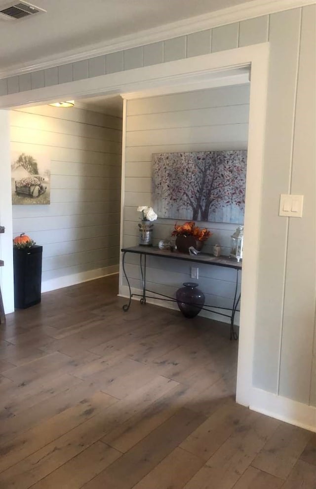 hall with dark wood-type flooring and ornamental molding