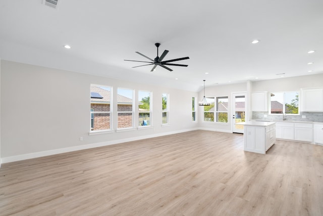 unfurnished living room featuring sink, light hardwood / wood-style floors, and ceiling fan with notable chandelier