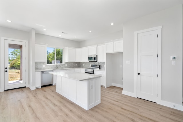 kitchen featuring sink, stainless steel appliances, a kitchen island, light hardwood / wood-style flooring, and white cabinets