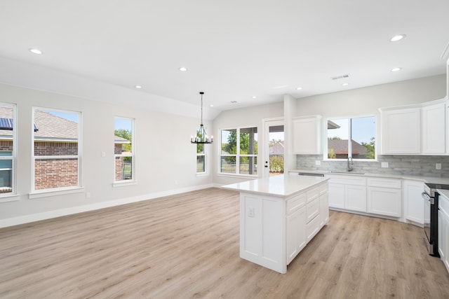 kitchen featuring a center island, white cabinets, light hardwood / wood-style flooring, tasteful backsplash, and a chandelier