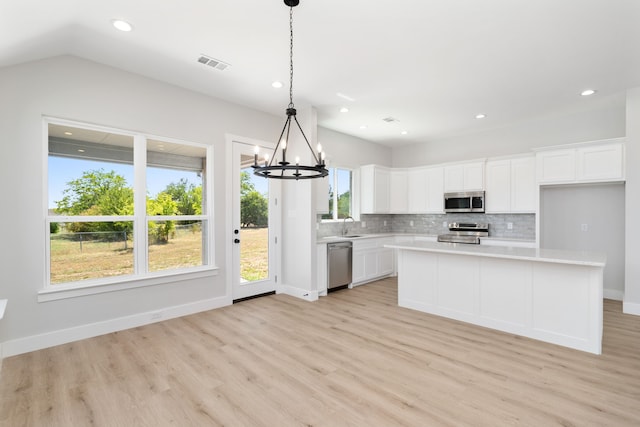 kitchen featuring appliances with stainless steel finishes, light hardwood / wood-style floors, white cabinetry, and a healthy amount of sunlight