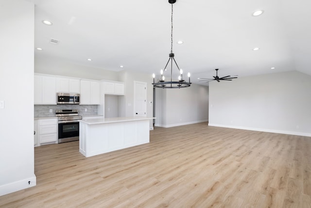 kitchen with stainless steel appliances, light hardwood / wood-style flooring, white cabinets, a kitchen island, and hanging light fixtures