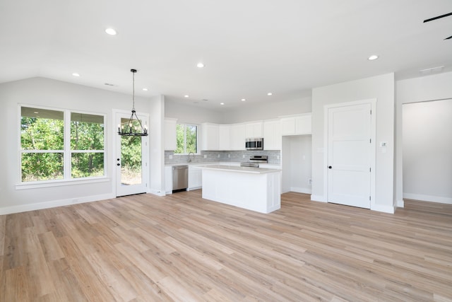 kitchen with white cabinets, a kitchen island, light wood-type flooring, and appliances with stainless steel finishes