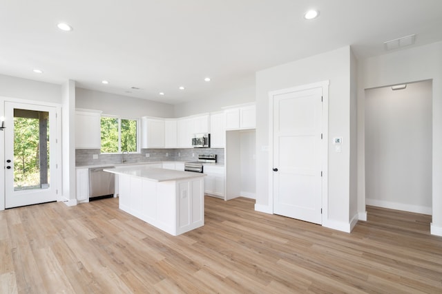 kitchen with white cabinets, appliances with stainless steel finishes, a center island, and light hardwood / wood-style floors