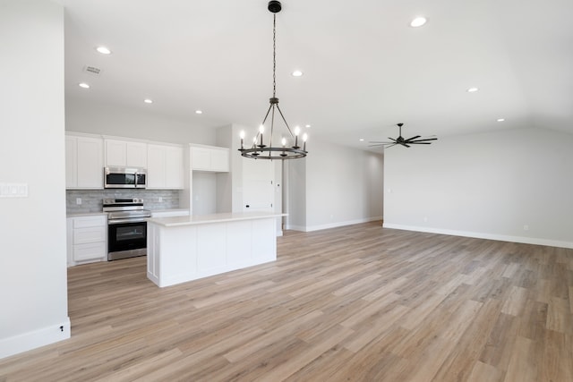 kitchen with white cabinets, decorative light fixtures, stainless steel appliances, and light hardwood / wood-style flooring