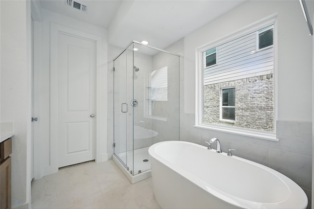 4182 Carter Ct, Denison, TX 75020 - bathroom featuring marble finish floors, vanity, a freestanding tub, a stall shower, and tile walls