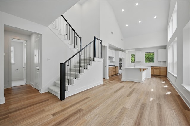 4182 Carter Ct, Denison, TX 75020 - unfurnished living room featuring high vaulted ceiling, stairs, light wood-type flooring, recessed lighting, and baseboards