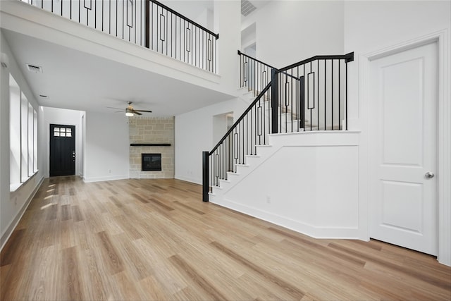4182 Carter Ct, Denison, TX 75020 - unfurnished living room with light wood-style flooring, ceiling fan, stairs, a high ceiling, and a fireplace