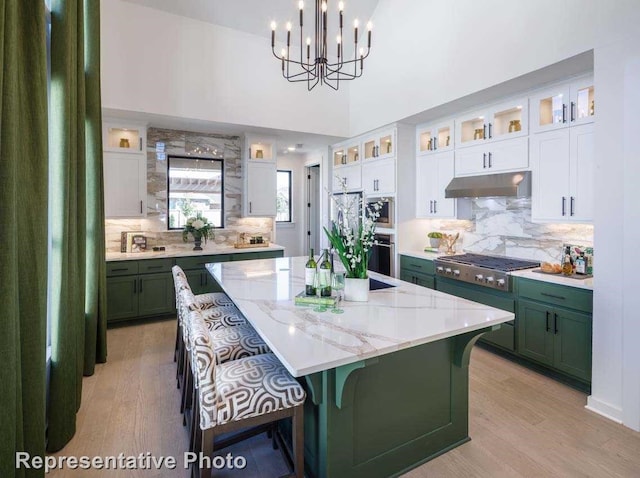 kitchen featuring appliances with stainless steel finishes, decorative light fixtures, light hardwood / wood-style flooring, white cabinets, and a kitchen island